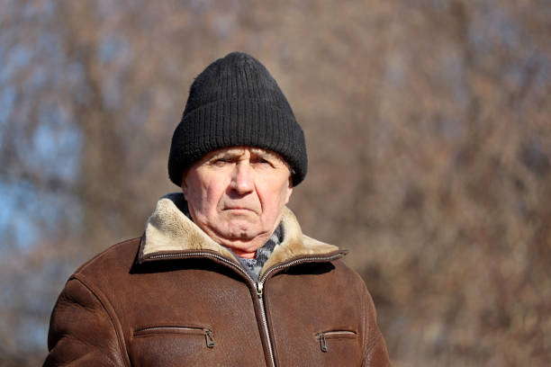 istock Portrait of elderly man with stern face standing on trees background 1307755334