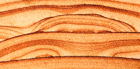 Ancient swirling patterns created in a cross section of orange colored sedimentary rock.