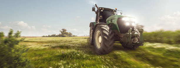 istock Tractor driving on a dirt road next to a field 1307759231