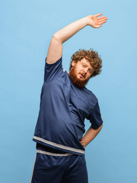 istock Young red-headed man in blue sports uniform isolated on blue background. 1307760054
