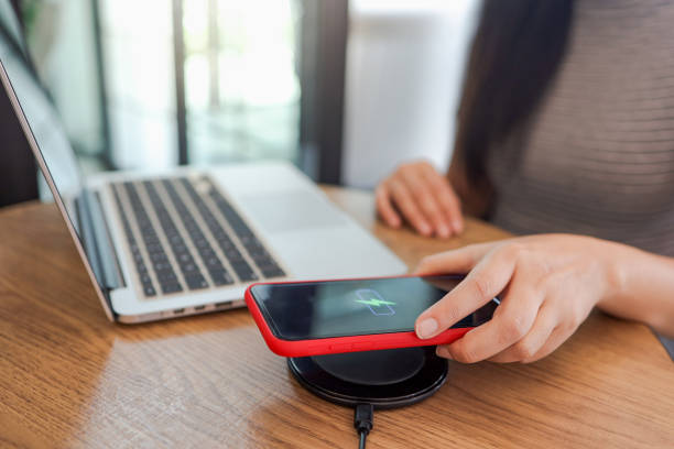 istock Charging mobile phone battery with wireless charging device in the table. Smartphone charging on a charging pad. Mobile phone near wireless charger Modern lifestyle concept. 1307760422