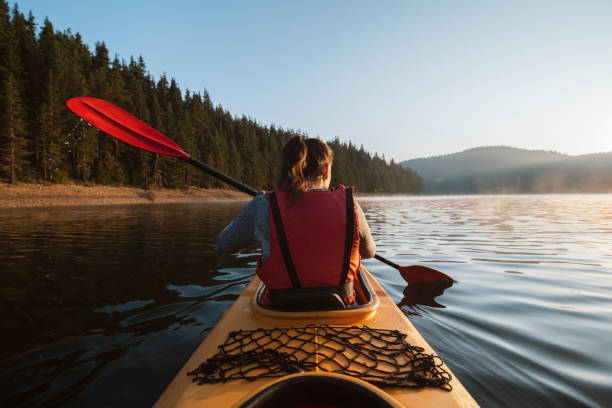 Sometimes this is all i need. A rear view of a woman kayaking and exploring mountain lake. kayaking stock pictures, royalty-free photos & images