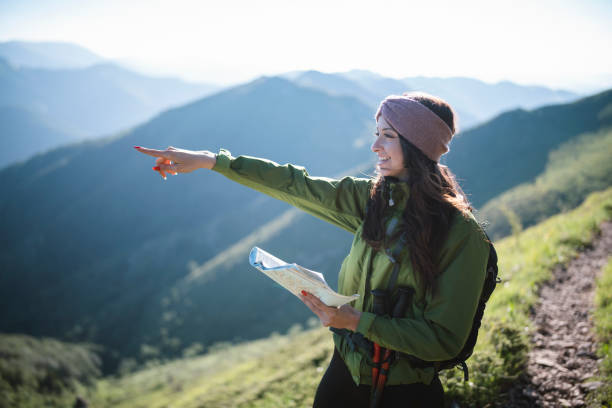 istock Woman on a hiking trip holding map and looking at beautiful view. 1307760490