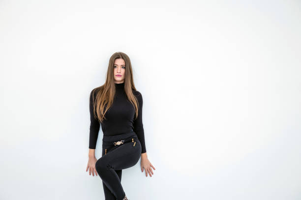 Portrait of young beautiful woman with long brown hair in black clothes. A ray of light shines on an attractive girl