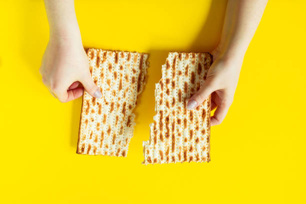 szczęśliwa pascha. tradycyjny chleb matzo w rękach na żółtym tle. żydowskie święto pesach, miejsce na tekst. - matzo passover cracker judaism zdjęcia i obrazy z banku zdjęć