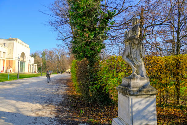 December 2020 Parma, Italy: Classical woman statue in park parco Ducale across bushes, building and people