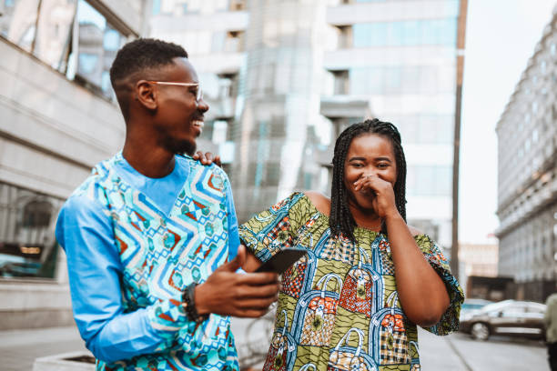sonriente pareja africana con colorida ropa tradicional pasando tiempo afuera en el centro de la ciudad - cardigan men african ethnicity african descent fotografías e imágenes de stock