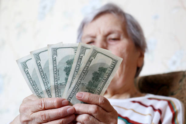 istock Elderly woman counts dollars in hands 1307763491