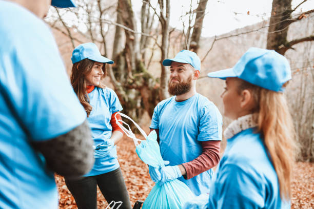 istock Smiling Friends Collecting Trash From Forest 1307764525