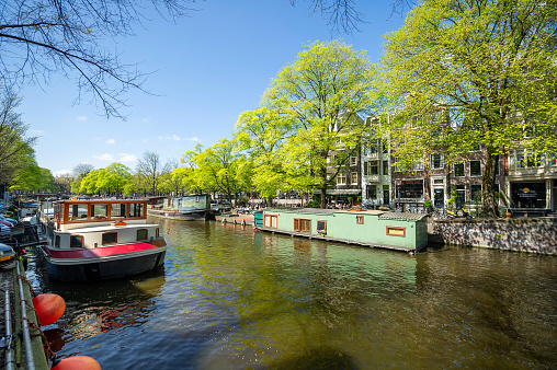 Amsterdam, Netherlands - April 19, 2014: Boats drive between houseboats in the capital's canals.