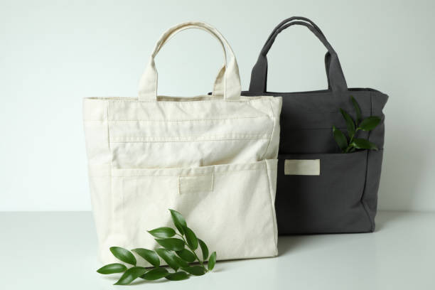 istock Stylish eco bags and twigs on white background 1307768144