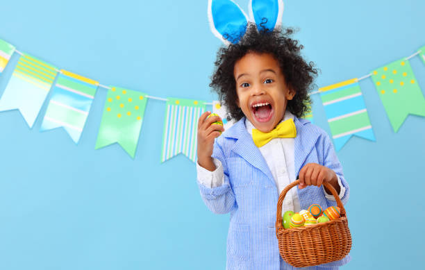 Astonished black child yelling happily in blue studio with Easter basket in hand