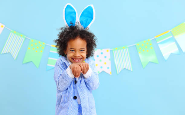 istock Adorable black kid imitating bunny in blue studio 1307768816