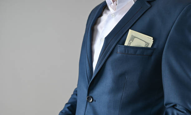 istock man in suit puts money in his pocket, corruption concept 1307770923