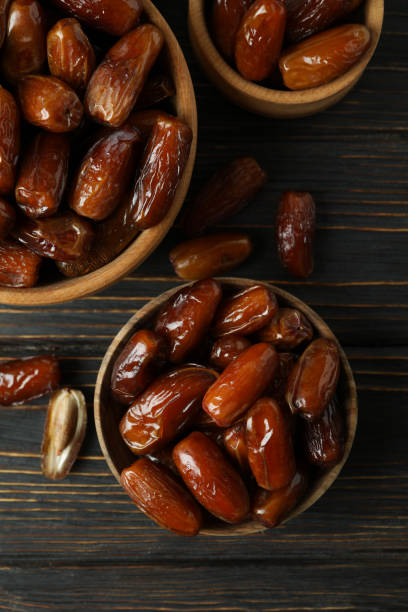 istock Bowl with dried dates on wooden table 1307771088