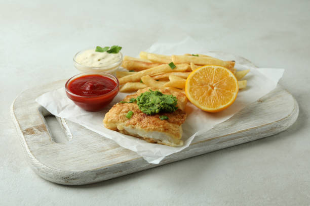 istock Concept of tasty eating with fried fish and chips on white textured table 1307771641