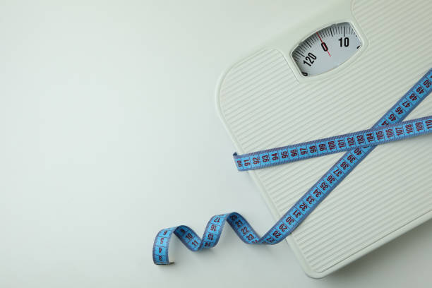 istock Scales with measuring tape on white background 1307773889