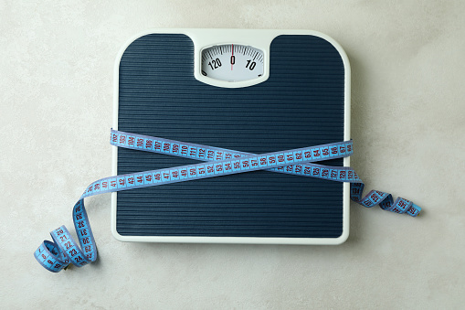 Scales with measuring tape on white textured background