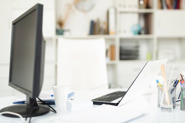 istock Office desk for two with laptop and desktop computer and disposable cups 1307774175