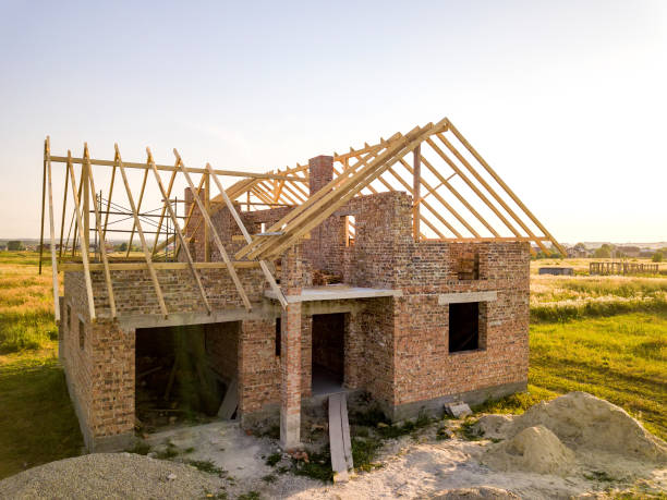 istock Unfinished brick house with wooden roof structure under construction. 1307775025