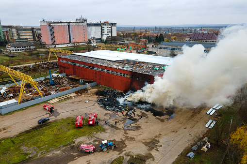 Aerial view of firemen fighting with fire near old factory biulding in industrial area.