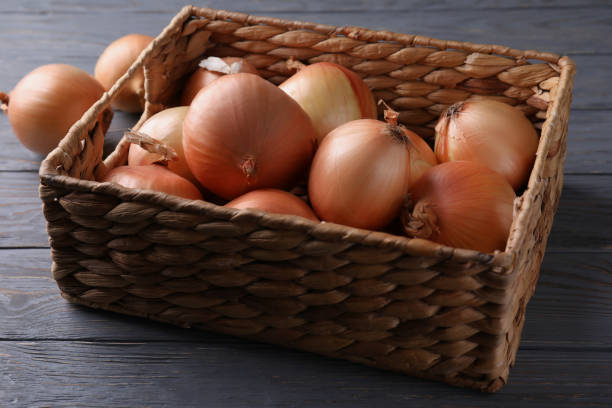 istock Basket with fresh onion on wooden background 1307776773