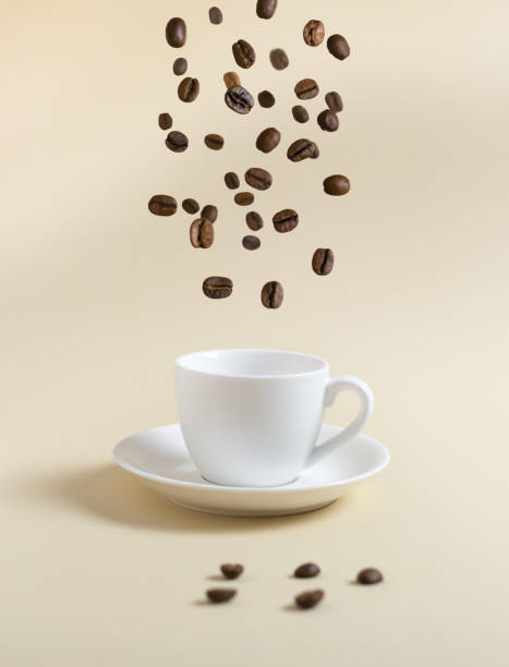 istock Coffee beans are flying into a white espresso cup on a yellow background. 1307778105