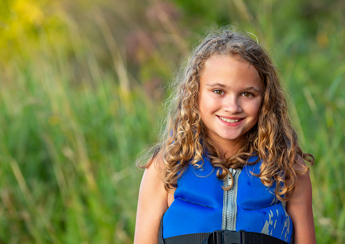 Cute girl, sitting on a moving pontoon boat, smiling and enjoying the wind and the ride on The Menominee River on the border of Northern Michigan and Wisconsin.
