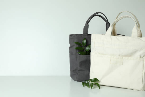 istock Stylish eco bags and twigs on white background 1307780557