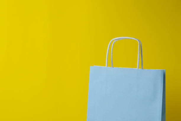 istock Blank paper bag against yellow background, space for text 1307782076