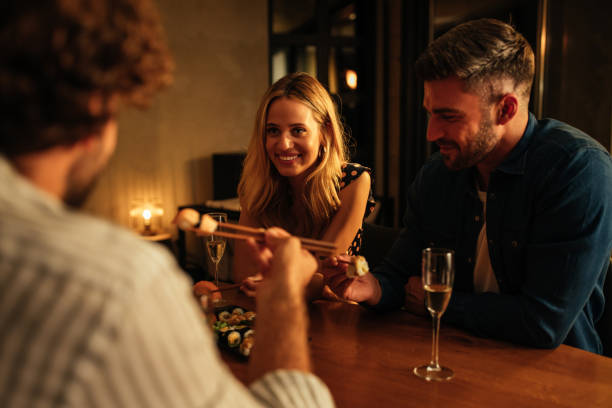 istock Friends sitting at the dining table and eating sushi 1307783766