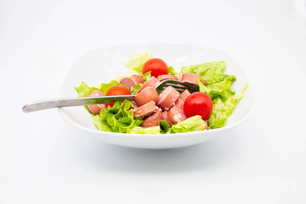 istock Fresh mixed salad with wurstel in a bowl. Raw salad on white background. 1307784148
