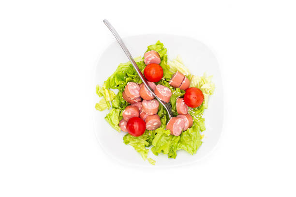 Fresh mixed salad with wurstel in a bowl. Raw salad on white background. Top View