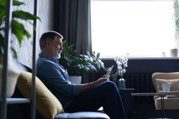 istock Mature handsome man websurfing on tablet at home. 1307786422