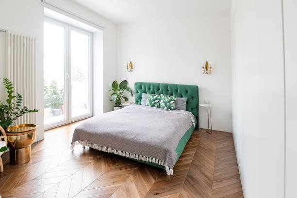 Interior of a bedroom with green wood-paneled walls in a rustic vacation home with a comfortable bed