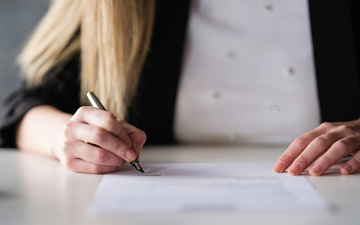 Businesswoman Signing Legal Paper In Office