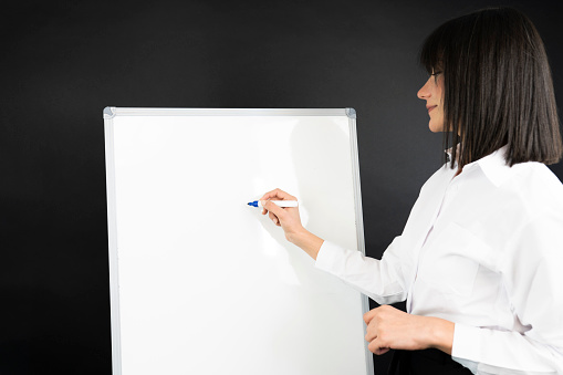 female writing on white board with her marker pen during conference meeting in office conference room