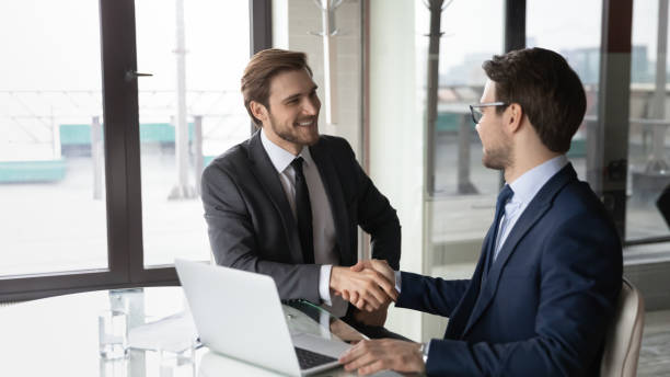 Smiling businessmen shake hands at office meeting Wide banner view of smiling businessmen shake hands close deal make agreement after successful negotiations in office. Happy male business partners handshake get acquainted greeting at meeting. constricted stock pictures, royalty-free photos & images