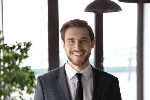 Headshot portrait of smiling Caucasian businessman pose at workplace Profile picture of smiling young Caucasian businessman in formal suit posing in office. Close up headshot portrait of happy motivated male CEO or director at workplace. Leadership, success concept. real estate agent photos stock pictures, royalty-free photos & images
