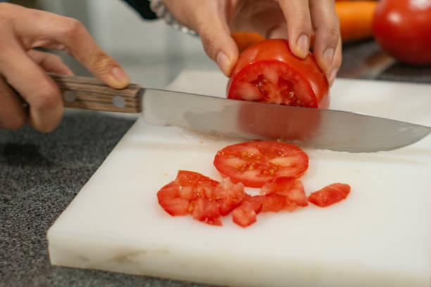 istock woman cutting vegetables tomato on cutting board 1307793108