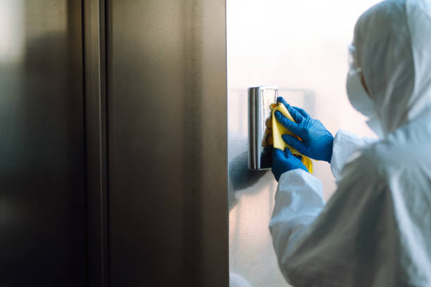 istock Disinfecting  of the elevator. Man in a protective suit and mask sprays disinfectants buttons of the lift. 1307797541