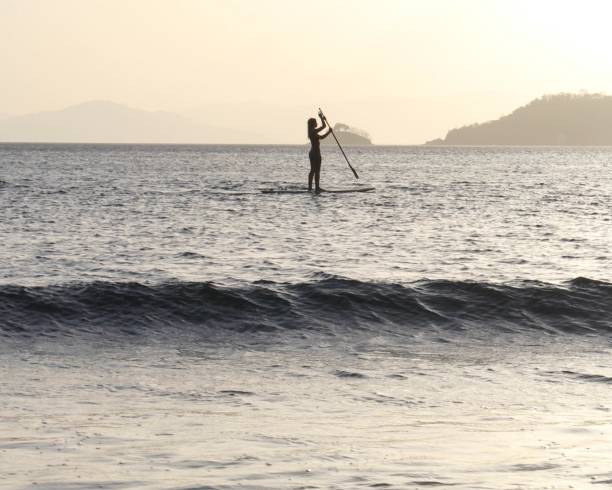istock Young woman paddles through open waters on SUP at sunrise 1307798771