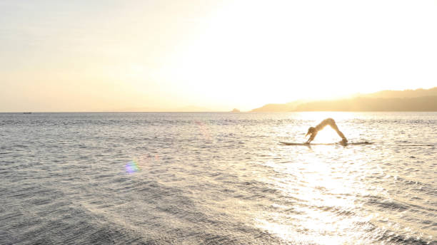 istock Young woman performs yoga on paddle board in the morning 1307798857