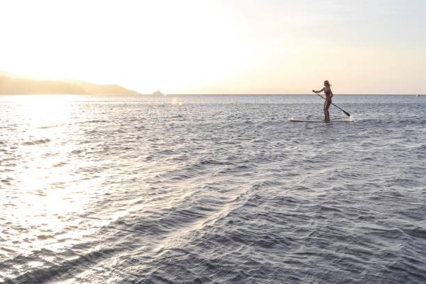 istock Young woman paddles through open waters on SUP at sunrise 1307798926