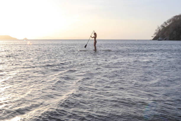 istock Young woman paddles through open waters on SUP at sunrise 1307798953