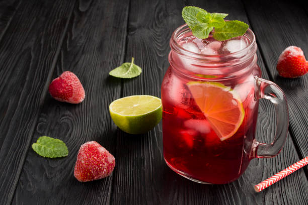 istock Cold lemonade with strawberries and lime on the black wooden  background 1307799136