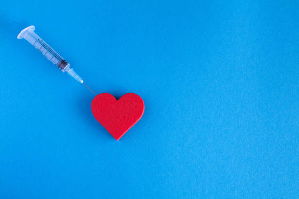 istock Red heart and syringe on the blue  background.Top view.Copy space. 1307800525