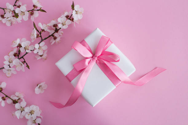 istock Gift with pink bow and flowering tree branches on the pink background 1307800561