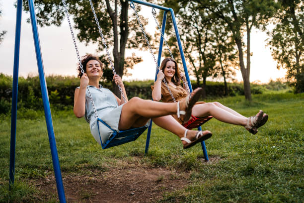 istock Two women riding swings in park 1307801863