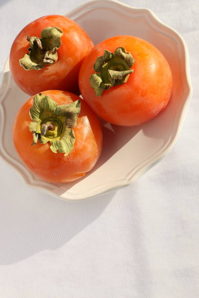 istock Fresh Ripe Persimmons on a White Classic Design Plate, Paradise Palms 1307802972